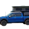Pickup mit aufgebautem INNature Black Stone Ilmenite Pop-up-Truck-Camper und ausgefahrenem Hubdach auf einem blauen Fahrzeug.