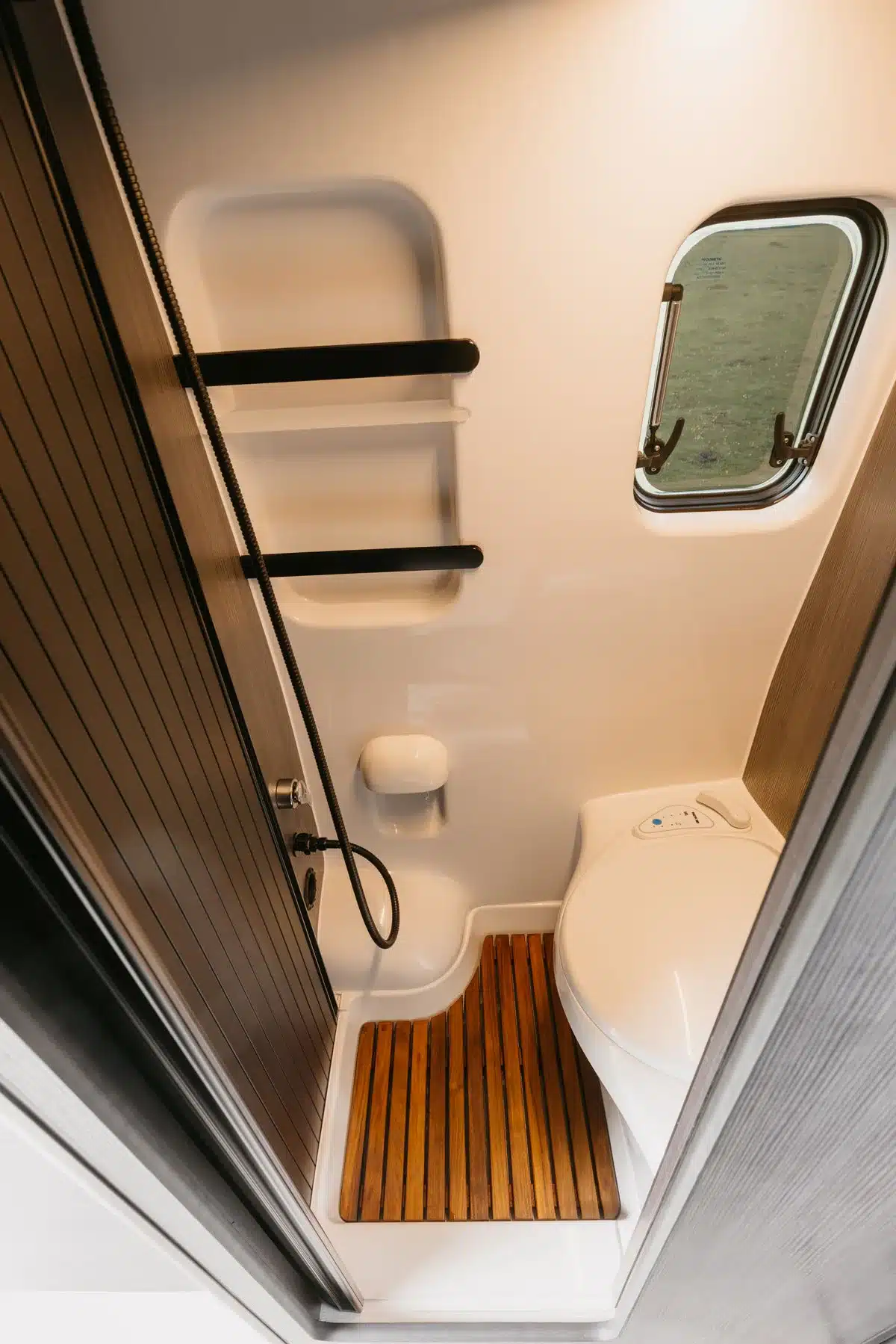 Innenansicht des Badezimmers im IPAR Furgoneta Camper NORANTZ mit Dusche, WC und Fenster.