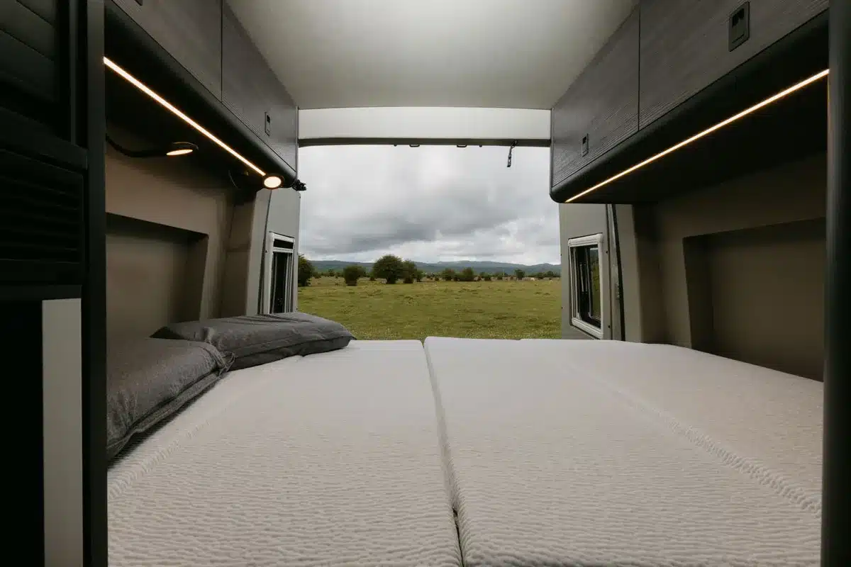 Innenansicht des NORANTZ Campers mit aufgeklapptem Bett und offenem Heck, Natur im Hintergrund