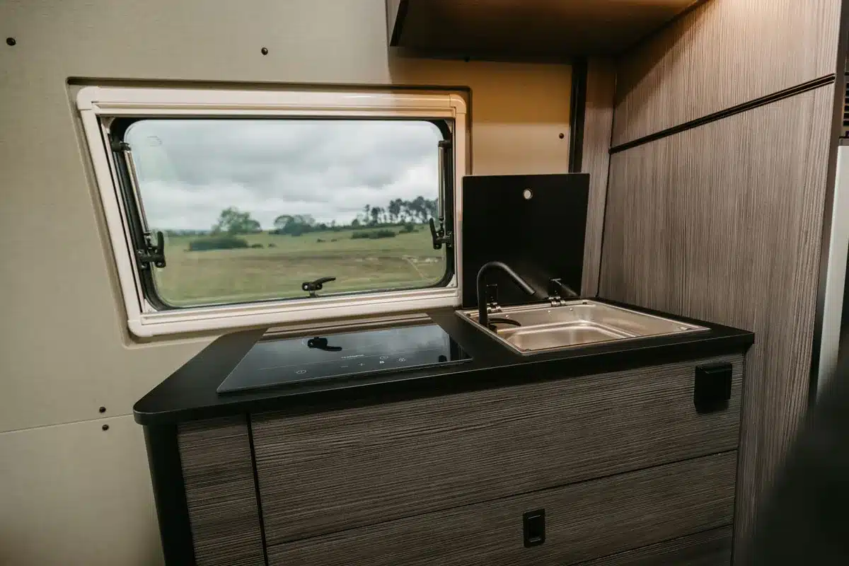 Camperküche mit großem Fenster, Induktionskochfeld und Spüle im IPAR Furgoneta Camper NORANTZ
