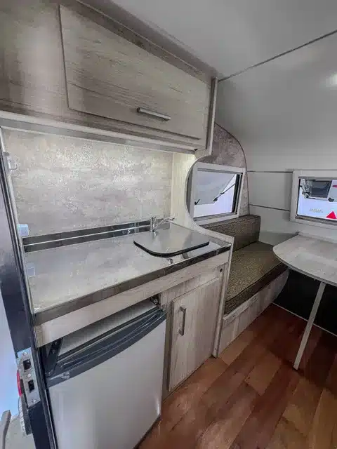 Innenaufnahme des ITATI 240 TFi Wohnwagens mit Küchenzeile, Spüle, Kühlschrank und Sitzbereich.