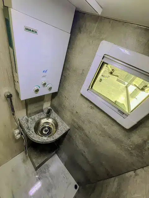 Badezimmer im ITATI 240 TFi Wohnwagen mit Edelstahlwaschbecken, Durchlauferhitzer und Fenster.