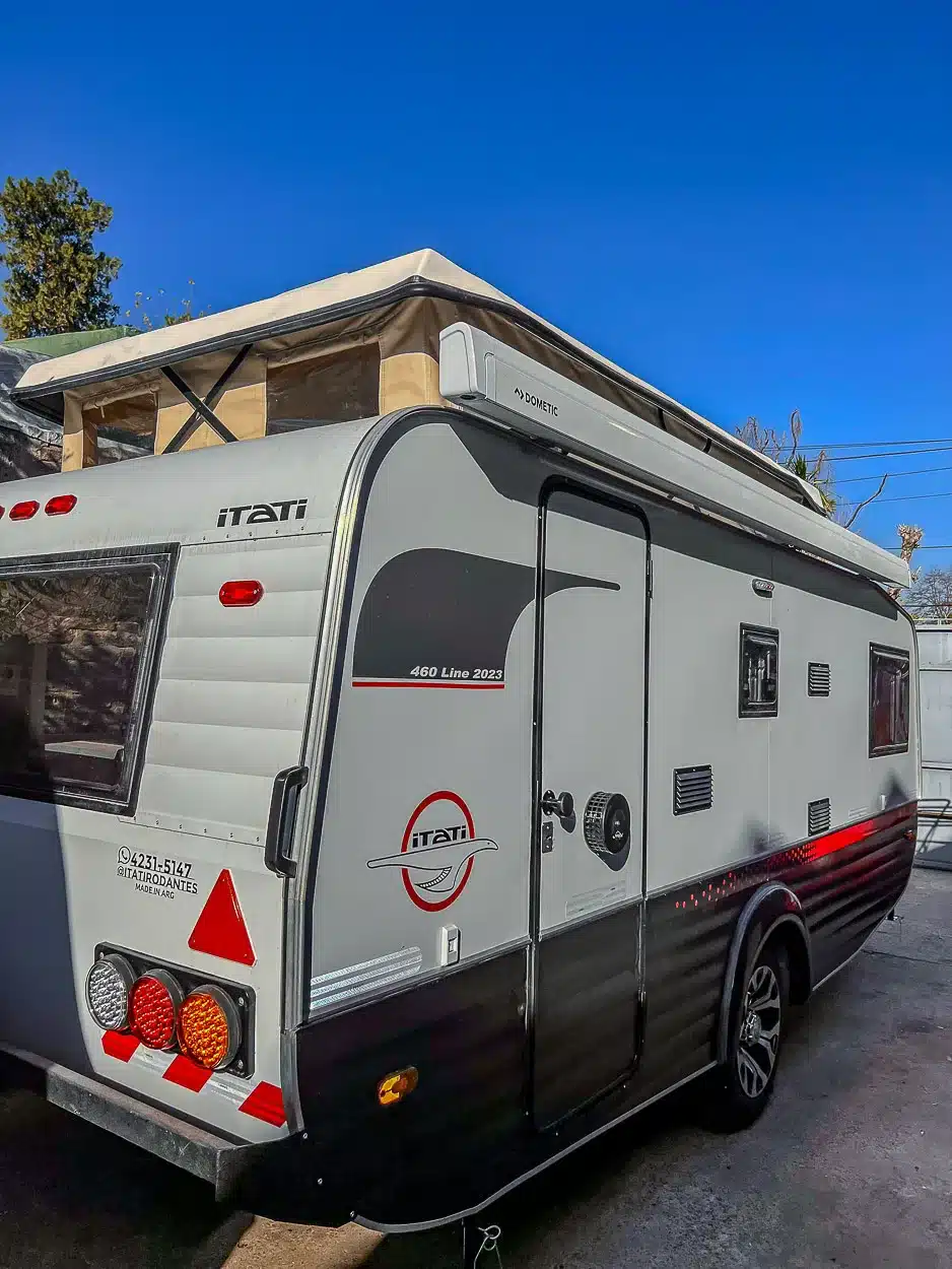 Seitenansicht des Itati 460 TLi Caravans mit ausgefahrenem Aufstelldach auf einem Stellplatz bei blauem Himmel.