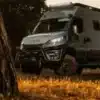 Expeditionsfahrzeug Iveco Daily 4x4 L3H2 im Gelände zwischen Bäumen, aufgenommen bei Sonnenuntergang