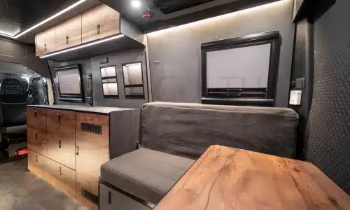 Moderner Innenraum eines ausgebauten Iveco Daily 4x4 Campers mit Sitzbereich und Holzverkleidung.