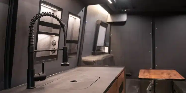 Iveco Daily 4x4 Camper: Blick auf Küchenblock mit Spültisch, moderner Armatur und Sitzgruppe im Innenraum.