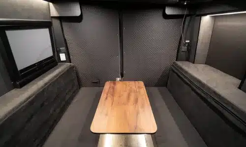 Blick in den modernen Wohnbereich eines Iveco Daily 4x4 Campers mit Tisch und Sitzflächen.