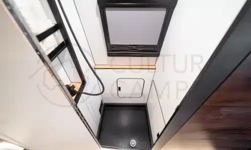 Duschkabine mit schwarzem Boden, Fenster und Stauraum im Innenraum eines Iveco Daily 4x4 Campers