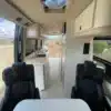 Innenraum des Jackson Campervans: Blick auf drehbare Sitze, Kücheneinbau und helle Ausstattung.