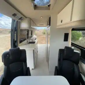 Innenraum des Jackson Campervans: Blick auf drehbare Sitze, Kücheneinbau und helle Ausstattung.