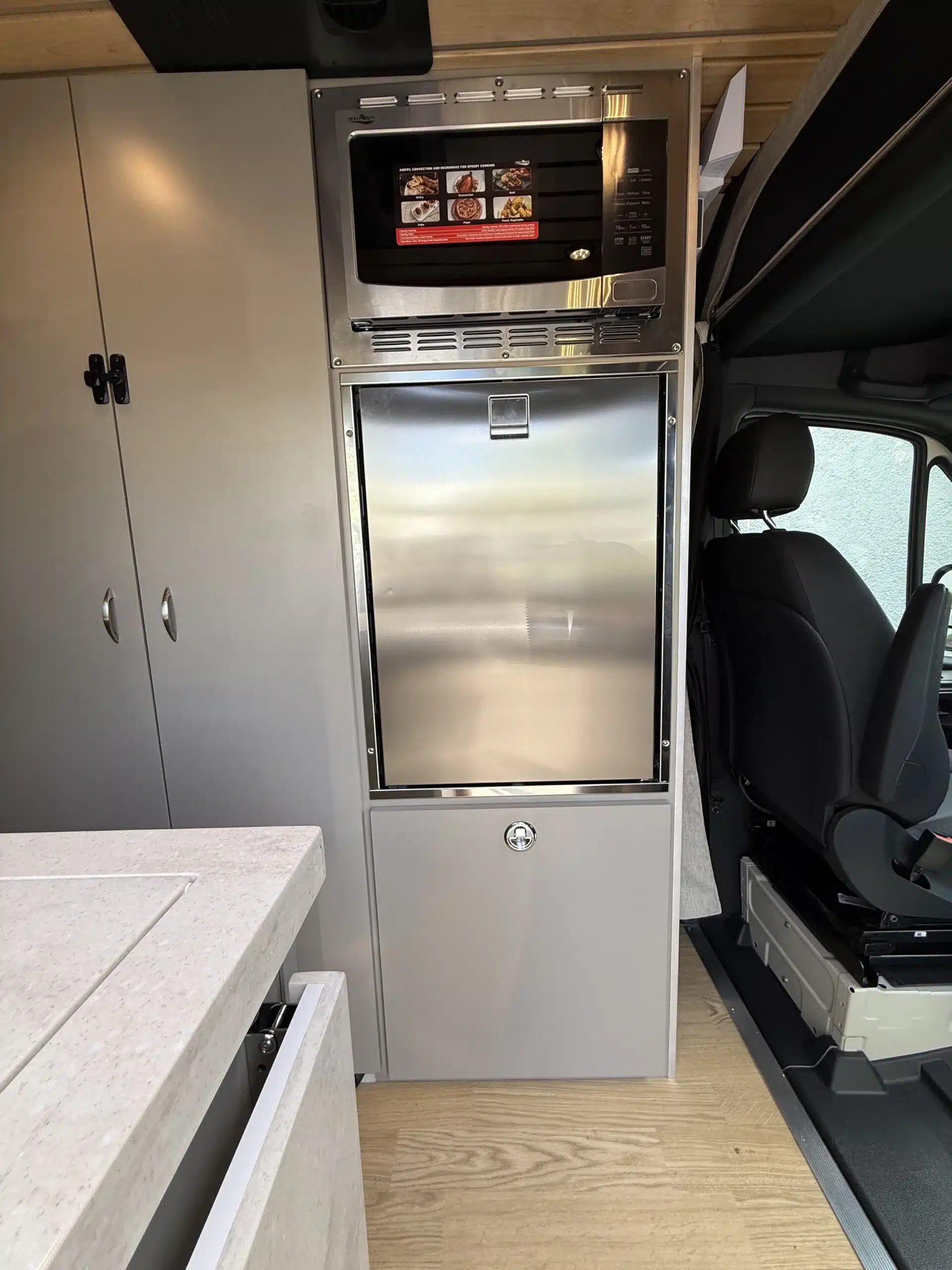 Campervan-Innenraum mit Küchenzeile, Mikrowelle und Edelstahl-Kühlschrank