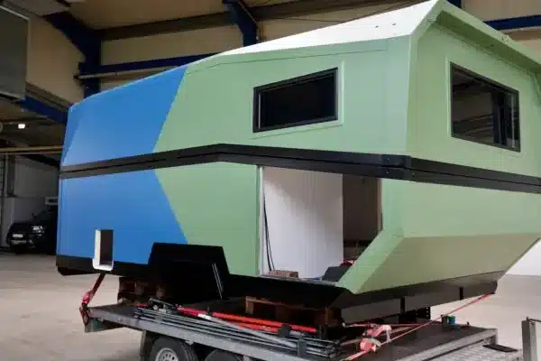 Die Laske LE410 Weltreisekabine als Rohbau mit markanten Fenstern und kantigem Design auf einem Trailer in einer Werkshalle.
