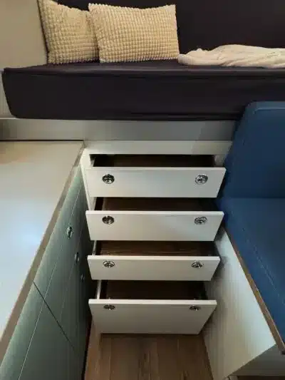 Offene Schubladen unter dem Bett in der Laske LE410 Expeditionskabine, daneben Sitzfläche und Kissen.
