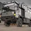 MAN HX60 Expeditionsmobil mit 4x4-Antrieb und individuell gestaltetem Aufbau für Fernreisen und autarkes Vanlife, fotografiert im Freien vor Industriegebäuden.