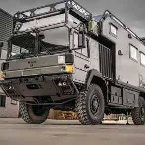 MAN HX60 Expeditionsmobil mit 4x4-Antrieb und individuell gestaltetem Aufbau für Fernreisen und autarkes Vanlife, fotografiert im Freien vor Industriegebäuden.
