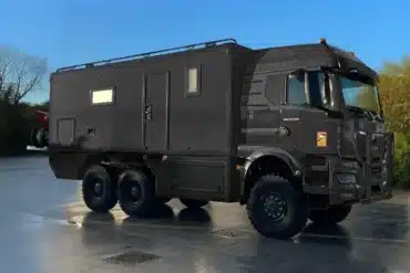 Schweres Allrad-Expeditionsmobil MAN TGS 33.520 6x6 mit großem Wohnkoffer auf Asphaltfläche.