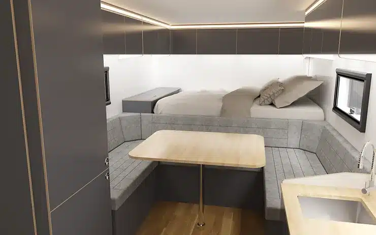 Moderner Innenraum eines Expeditionsfahrzeugs mit Sitzecke, Tisch und festem Bett