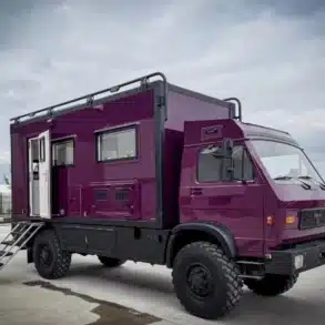 Lila MAN/VW 8.136 Expeditionsfahrzeug mit Wohnaufbau, ausgerüstet für Offroad-Reisen, seitlich fotografiert auf einem Parkplatz