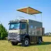 Mercedes Arocs K5 Flybridge Luxury Reisemobil mit ausgefahrener Flybridge auf einer Wiese