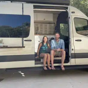Ein Mercedes Sprinter 170 Adventure-Van mit geöffneter Schiebetür; zwei Personen sitzen im Van.