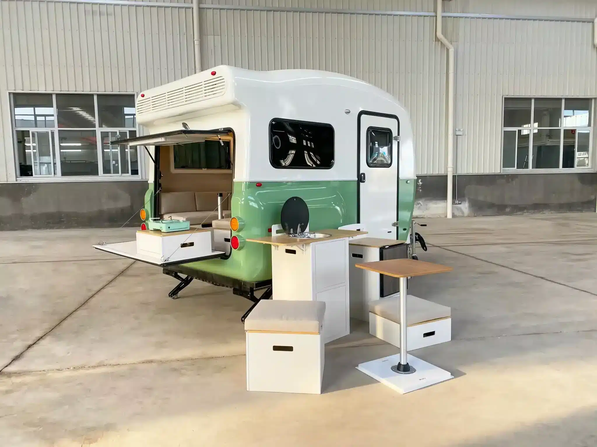 MOOI Mini Teardrop Camper mit geöffneter Heckklappe und ausgestatteter Außenküche im Werksumfeld