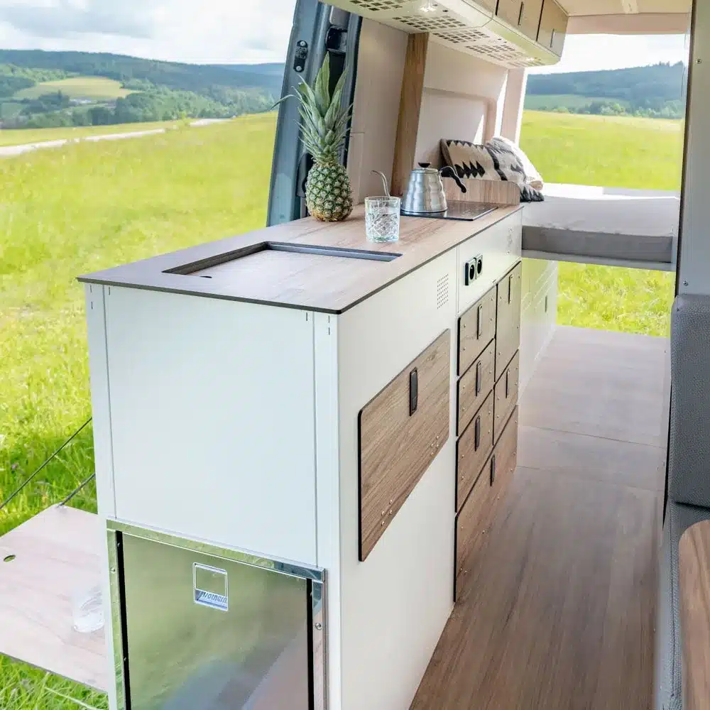 Integrierte Camperküche Moon Kitchen Solid Model 3 mit Holzfronten und Arbeitsfläche im modernen Kastenwagenausbau