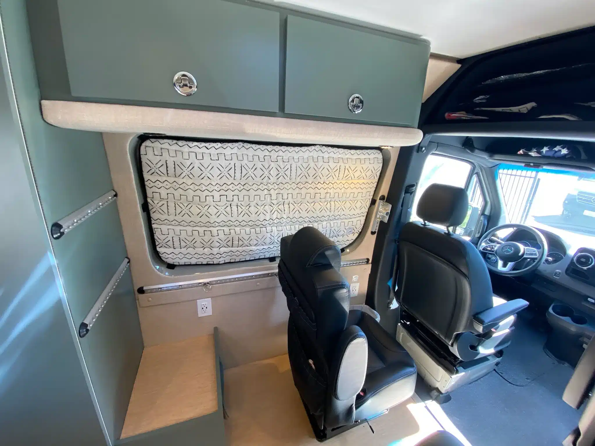 Innenraum eines Mercedes Sprinter 170 4x4 Campervans mit drehbarem Fahrersitz, zusätzlicher Sitzbank und maßgefertigtem Stauraum