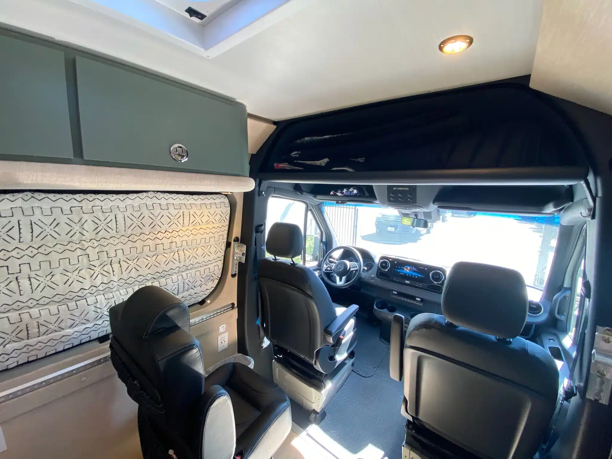 Innenraum eines ausgebauten Mercedes Sprinter 170 4x4 Campervans mit mehreren Sitzplätzen und individueller Ausstattung.
