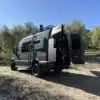 Mercedes Sprinter 144 AWD Campervan Nestor mit Dachträger und geöffneter Hecktür auf Waldweg