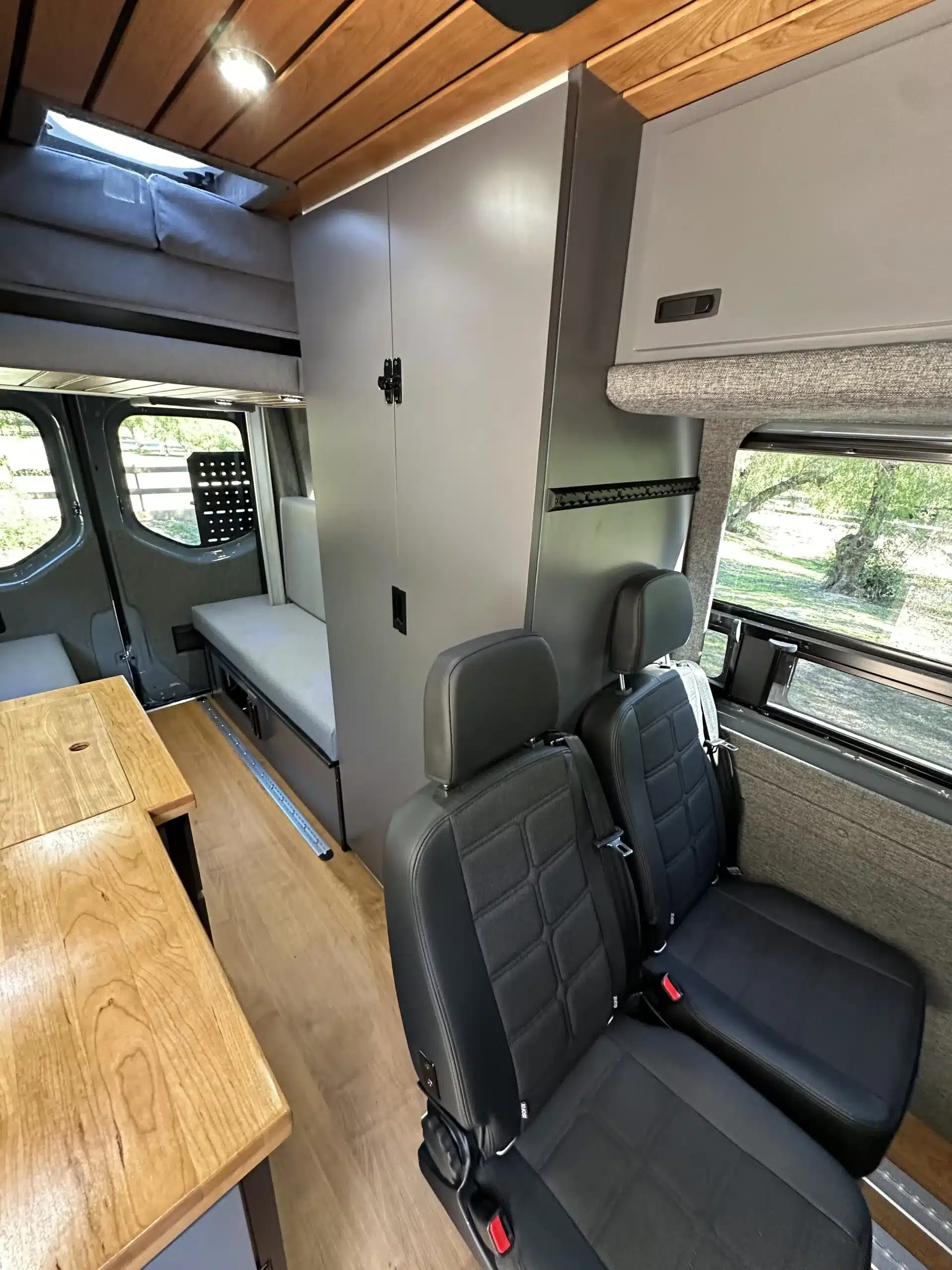 Wohnbereich mit variabler Sitzanordnung, L-Track-Sitzsystem und hellem Holzausbau im Nestor Campervan auf Sprinter 144 AWD