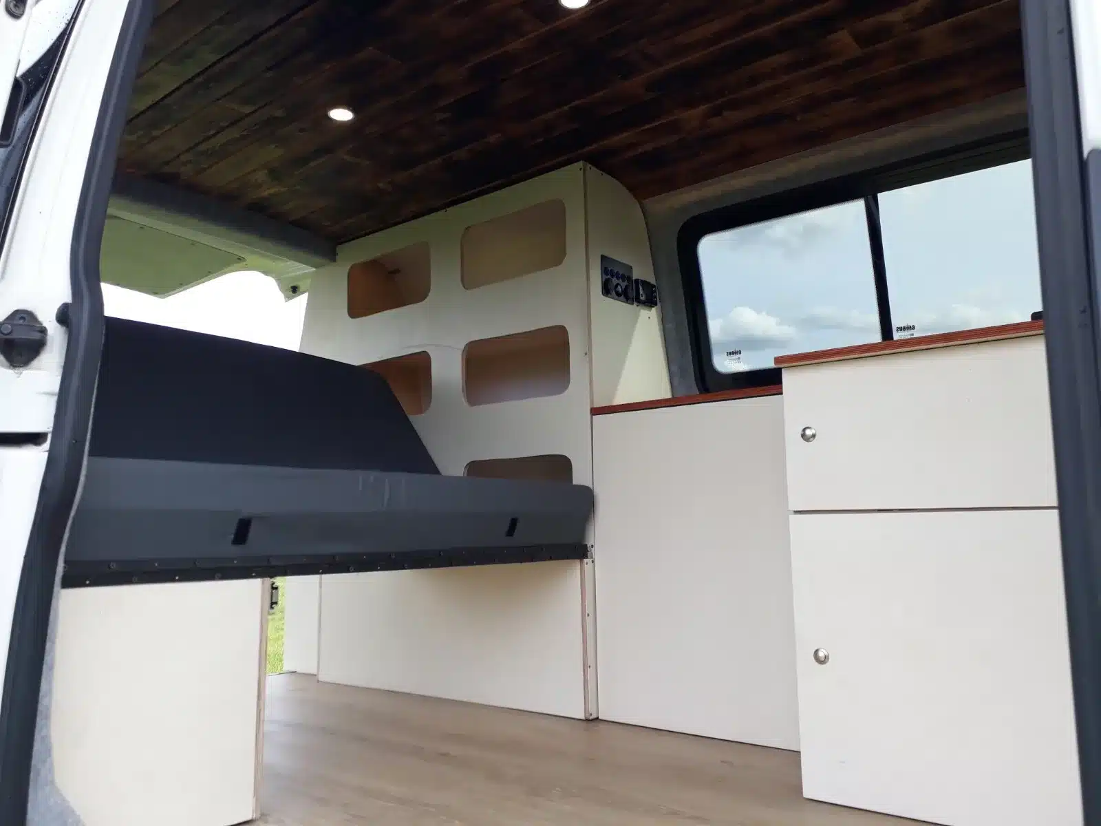 Innenraum eines VW T5 Transporters mit eingebautem Möbel-Bausatz, Klappbett, Schrank und Küchenmodulen
