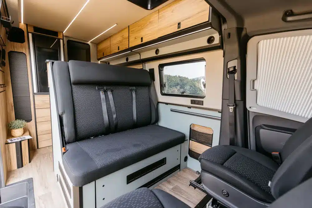 Blick in den Innenraum des NORANTZ EKI Camper Vans mit Sitzbank, Fahrerbereich und Stauraum