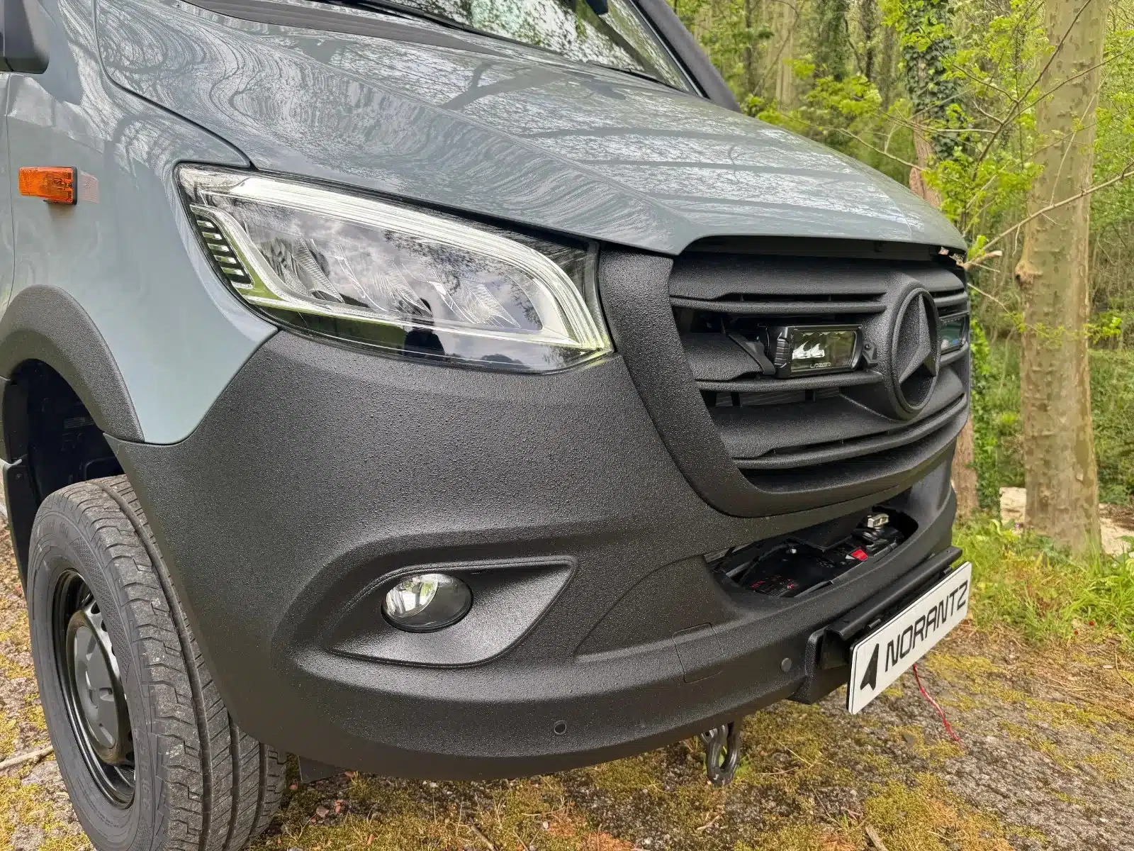 Detailansicht der Fahrzeugefront des NORANTZ IPAR 2 auf Mercedes Sprinter 4x4, ausgestattet für Offroad, im Wald