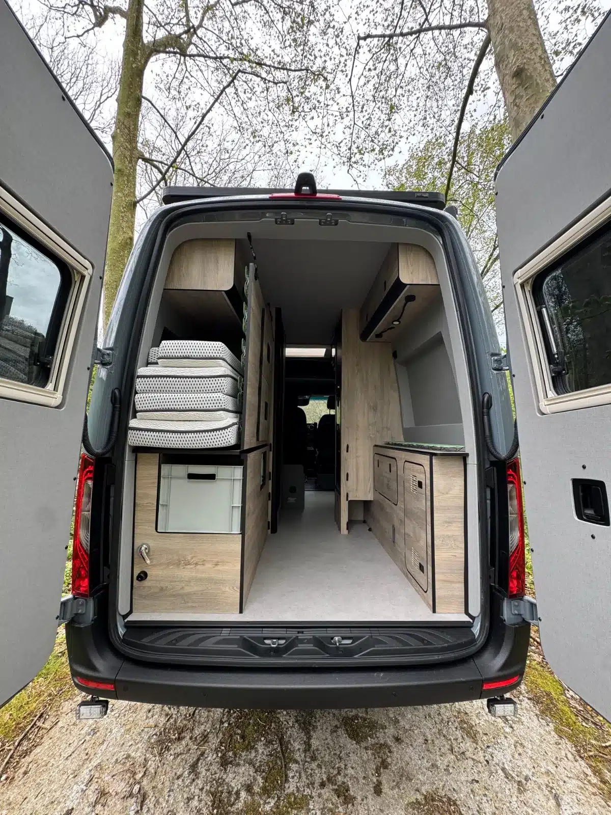 Offenes Heck eines Mercedes Sprinter 4x4 mit hochwertigem Vanlife-Ausbau von NORANTZ IPAR 2, sichtbarer Stauraum und Möbel