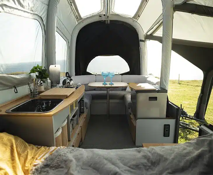 Innenansicht eines aufgeklappten Off-Road Air OPUS Faltcaravans mit Küchenzeile, Sitzgruppe und Blick nach draußen.