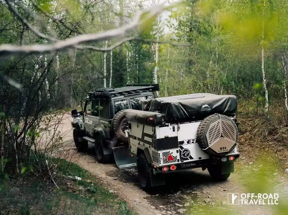 Patriot X1H Offroad-Trailer hinter einem Geländewagen auf einem Waldweg im Einsatz.