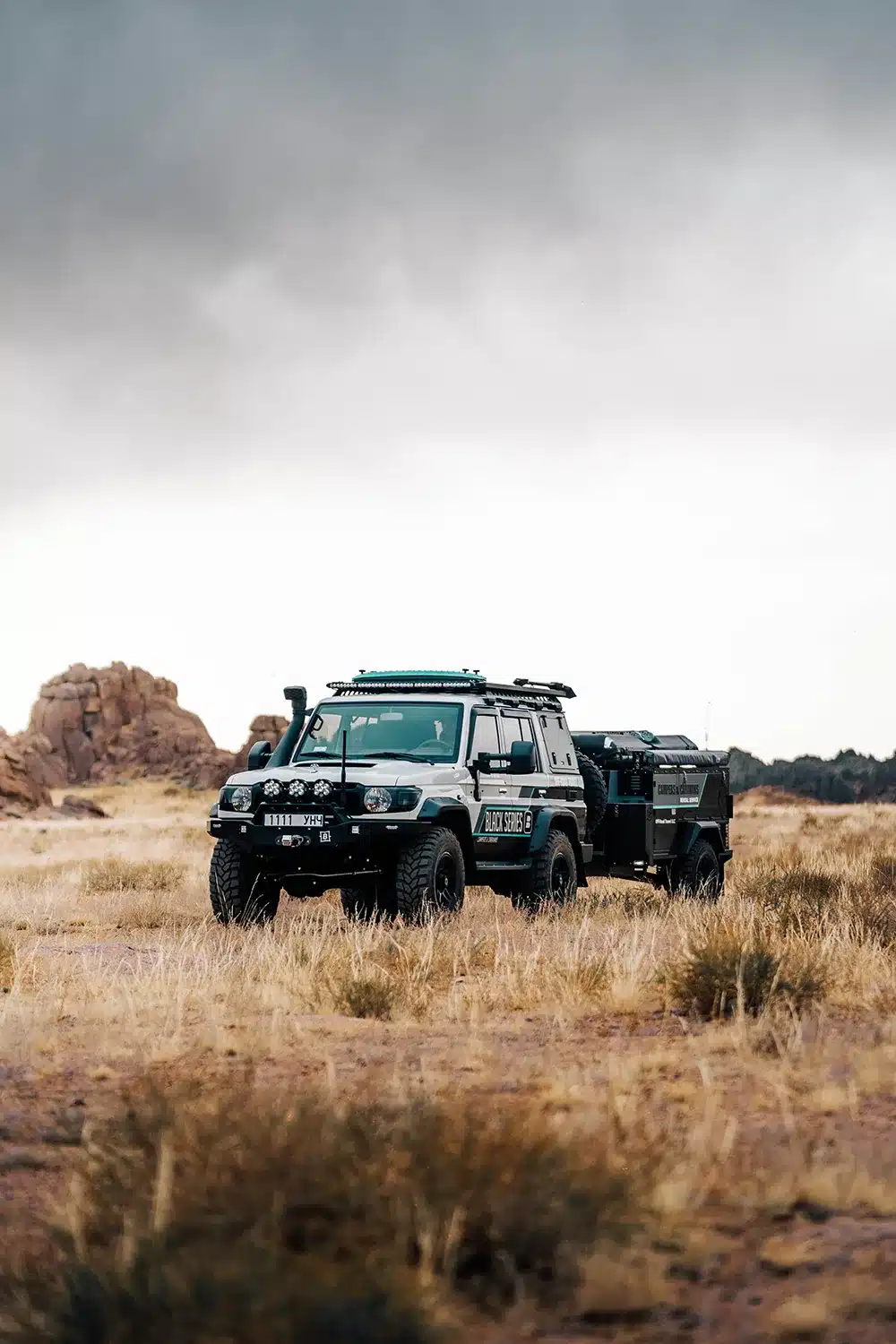 Patriot X1H Travel Trailer hinter einem Offroad-Fahrzeug in wilder Natur.