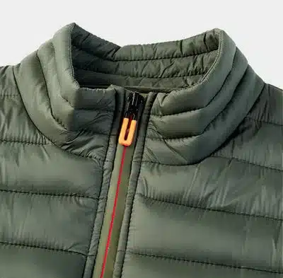 Nahaufnahme des hochgestellten Kragens und Reißverschlusses einer gesteppten, olivgrünen PAXSON Outdoor Weste