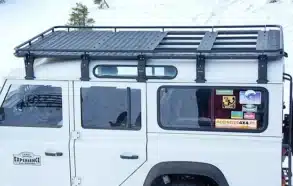 Qualan M Dachgepäckträger montiert auf einem weißen Land Rover Defender im Schnee