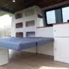 Innenraum eines Renault Trafic mit modular eingebautem Möbelbausatz inklusive Klappbett und Küchenzeile.