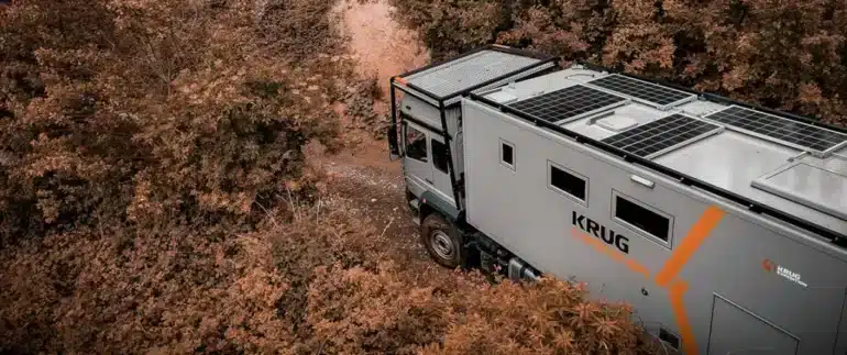 Rhino XL Business Expeditionsfahrzeug von Krug Expedition auf einem Waldweg, umgeben von Pflanzen