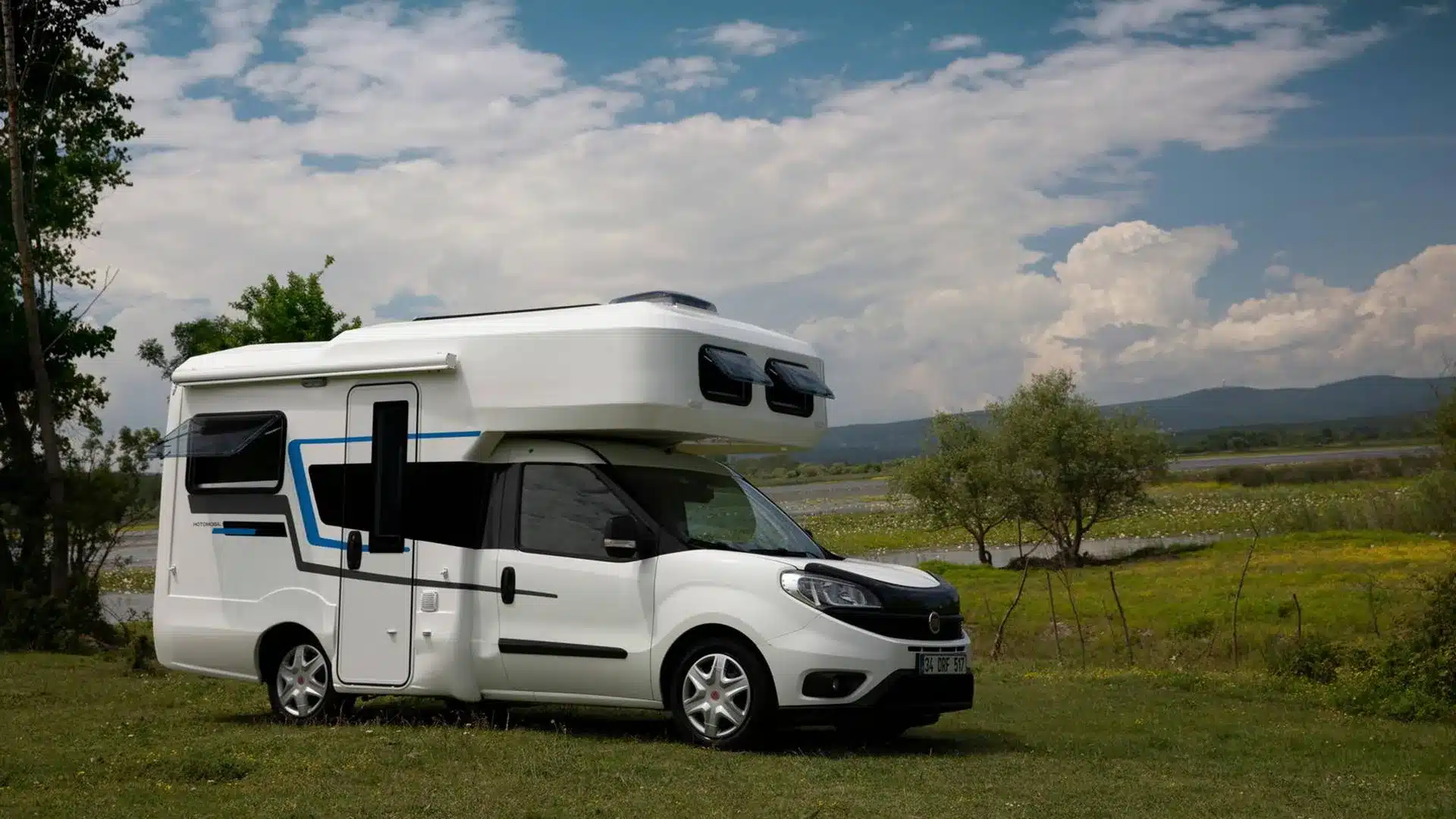 Ronin XL Motorhome auf Fiat-Chassis mit Monoblock-Fiberglaskabine, geparkt auf einer Wiese vor malerischer Landschaft.