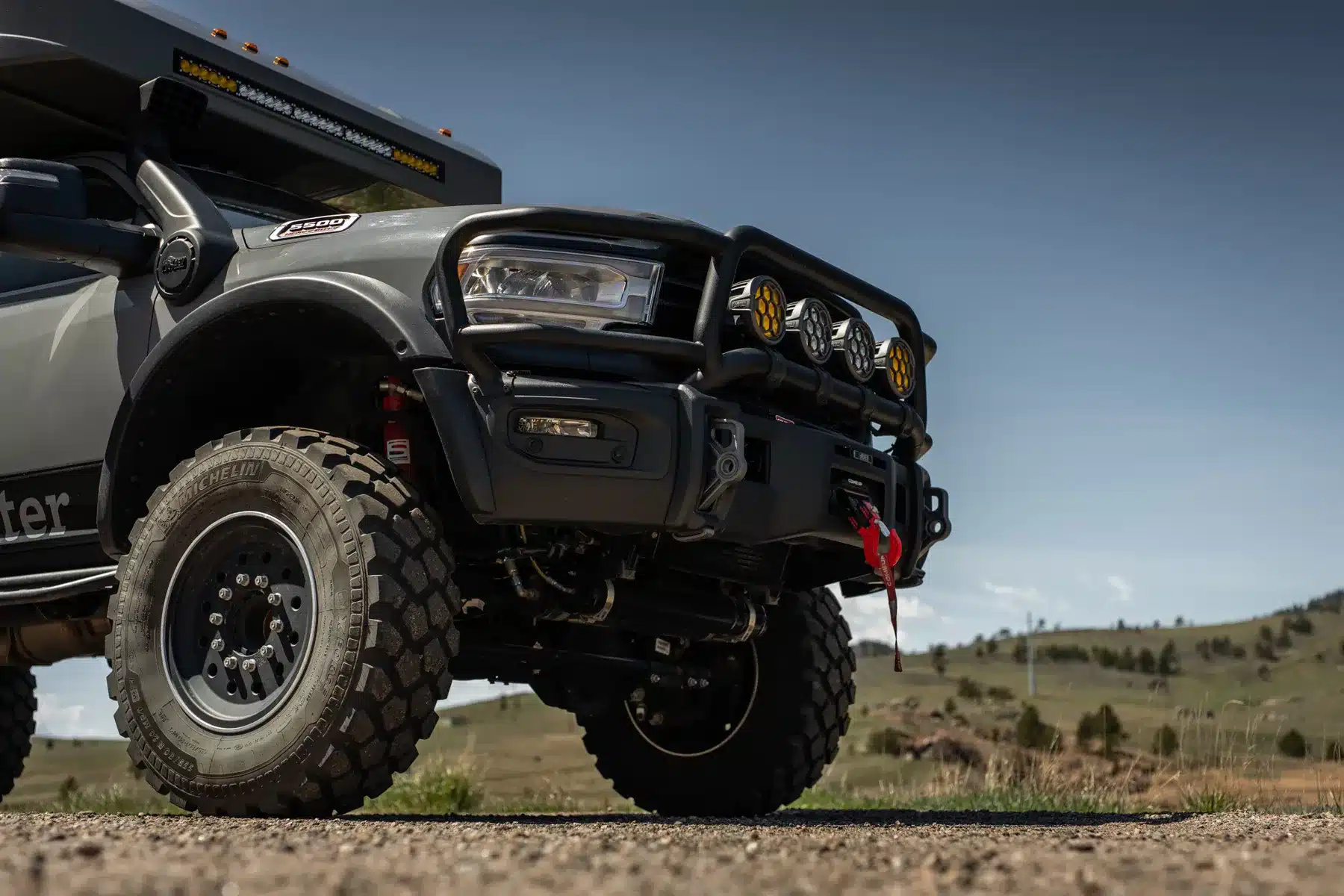Rossmönster Baja Plus mit Offroad-Bereifung, Zusatzleuchten und Lichtleiste vor Bergkulisse