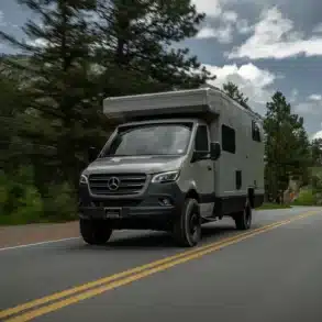 Rossmönster Havn Expeditionsfahrzeug auf Mercedes Sprinter fährt auf einer Landstraße durch bewaldete Gebirgslandschaft