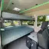 Doppeltes Plattformbett und Sitzbereich im Innenraum des 'The Amy' Mercedes Sprinter 144 Campervans