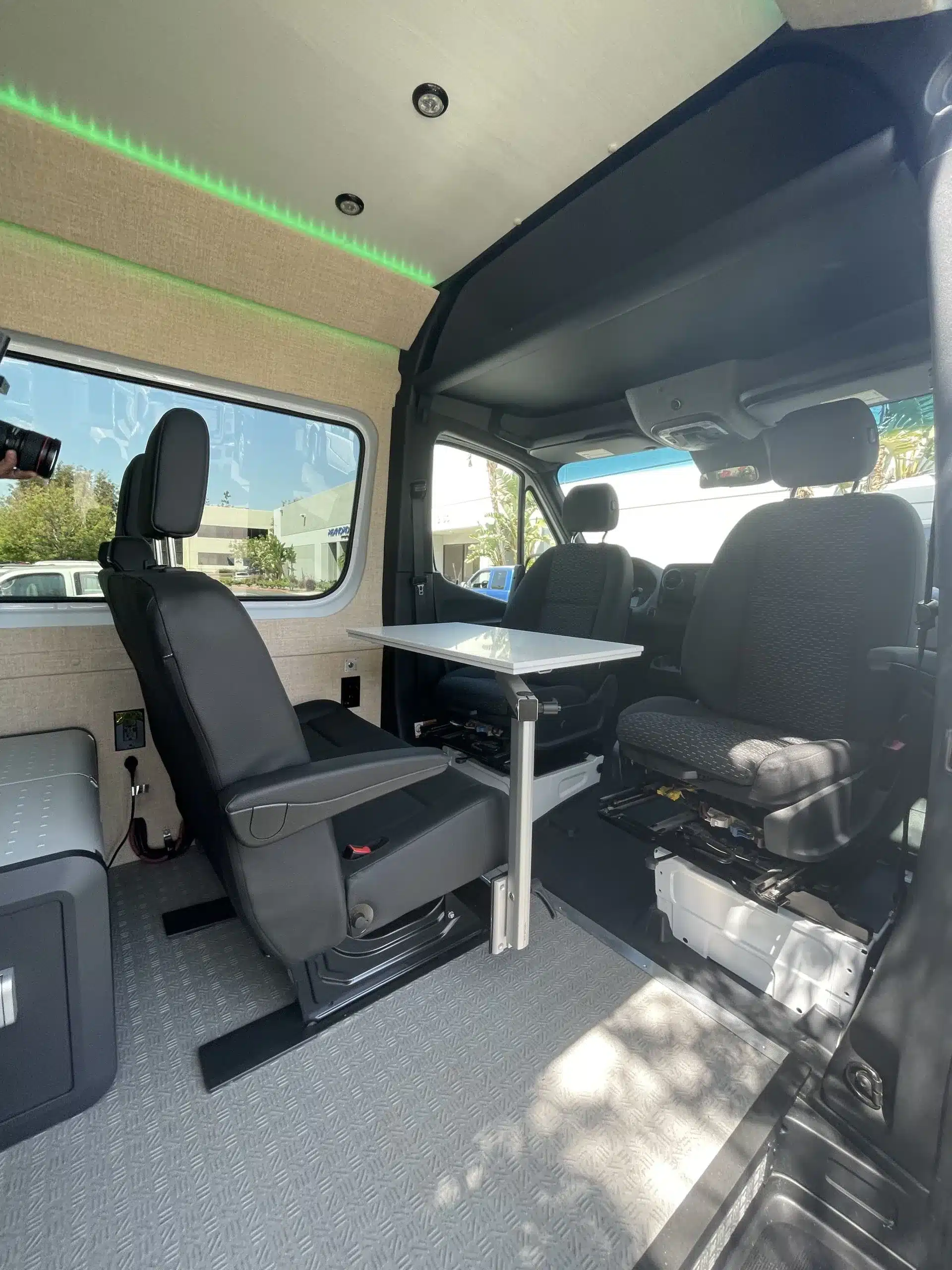 Wohnbereich im Familien-Abenteuervan The Amy: Sitzgruppe mit Tisch und drehbaren Sitzen im Mercedes Sprinter 144.
