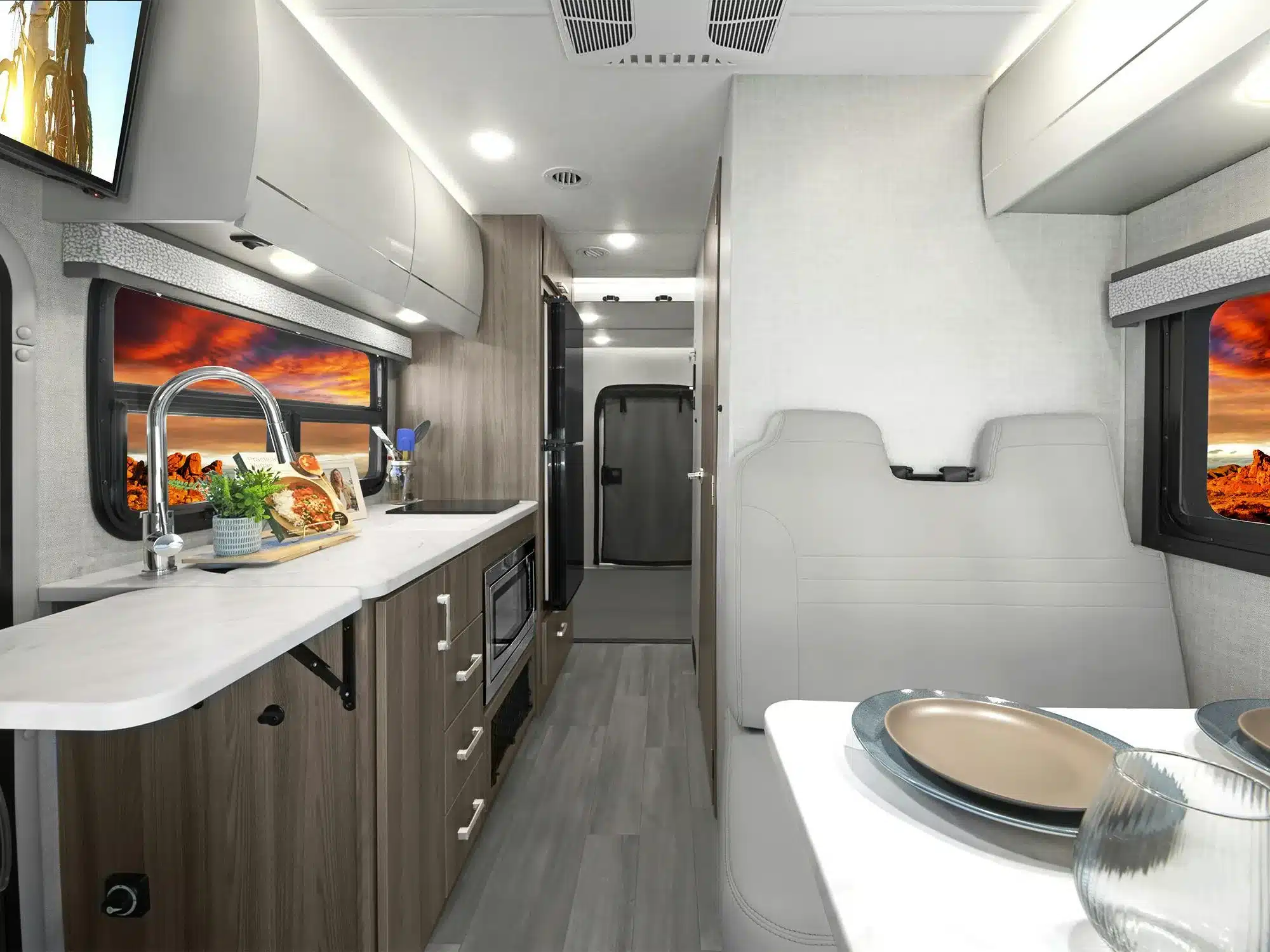Innenraum des Thor Gemini AWD 24KB mit Küchenzeile, Spüle, Herd, Mikrowelle und moderne Einrichtung.
