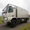 Seitenaufnahme des TITAN 62 UQX 4x4 Expeditionsfahrzeugs auf Mercedes Arocs 2053A Basis auf einer Landstraße.