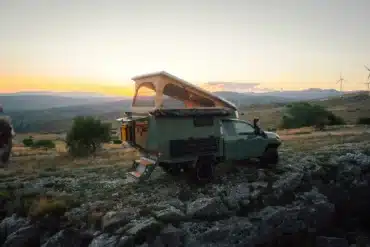 Toyota Hilux Trailcat Expeditionsfahrzeug mit geöffneter Wohnkabine und Aufstelldach in naturbelassener Umgebung bei Sonnenuntergang
