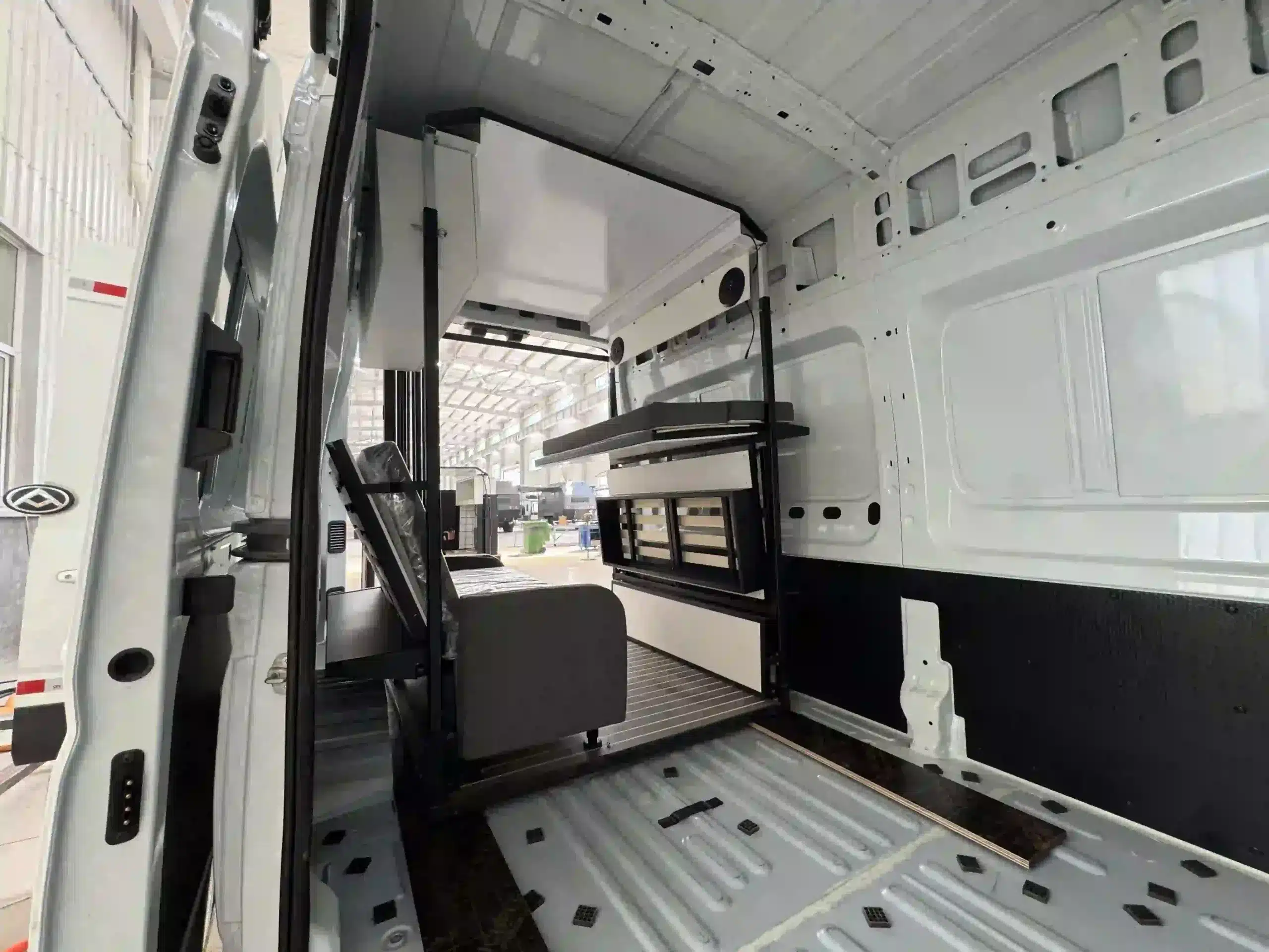 Innenansicht eines Transporters mit eingebautem VANBOX RV Home Box Modul, bestehend aus Küchenzeile, Sofa und Hochbett